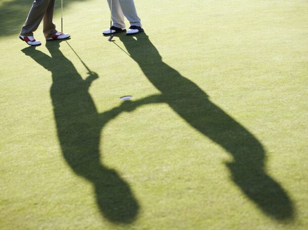 Golfers in silhouette on golf course