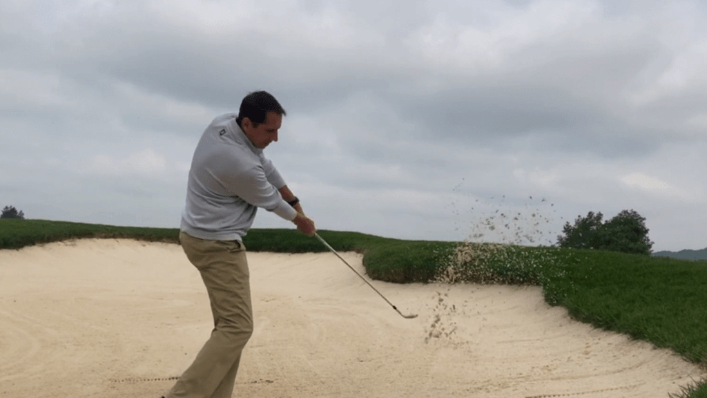 golfer taking a swing on bunker